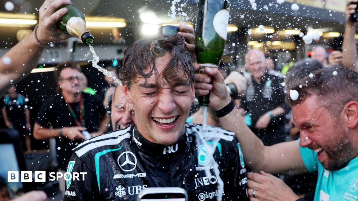 George Russell celebrating with Mercedes team members pouring champagne over him