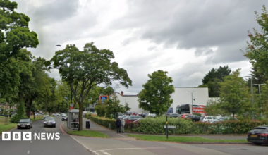 A busy road next to an Aldi superstore, with a road on the right hand side.