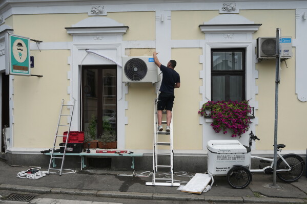 An worker installs a new air conditioning unit during a hot summer day in Belgrade, Serbia, June 30, 2026. (AP Photo/Darko Vojinovic, File)