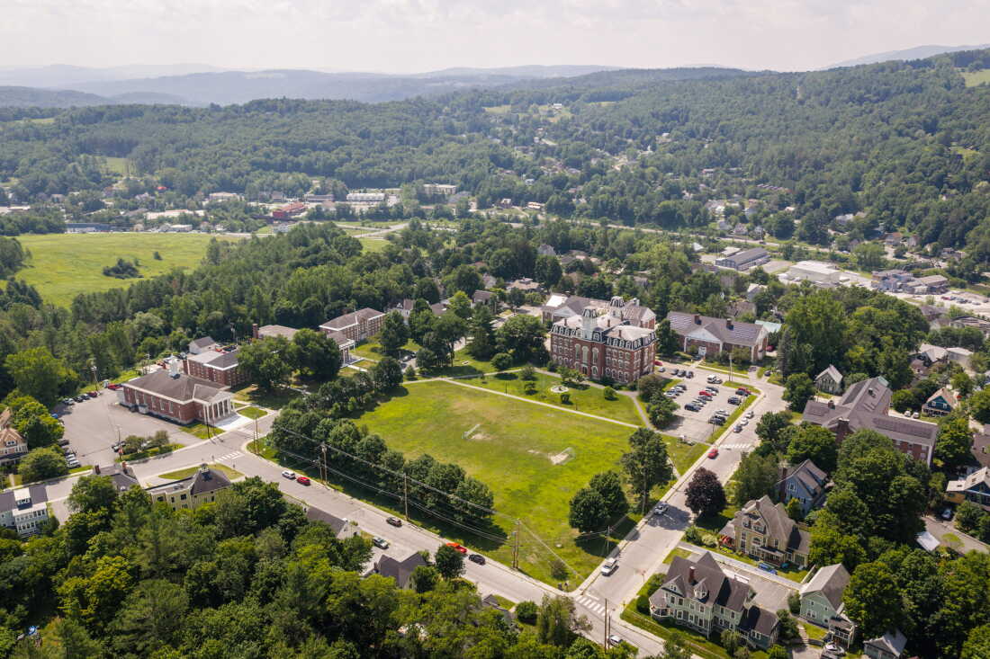 This photo taken from up high shows the campus of the Greenway Institute, which it bought from the Vermont College of Fine Arts and which dates back to the 19th century. The campus has multiple red-brick, older-style buildings and an open grassy area that's partially bordered by trees.