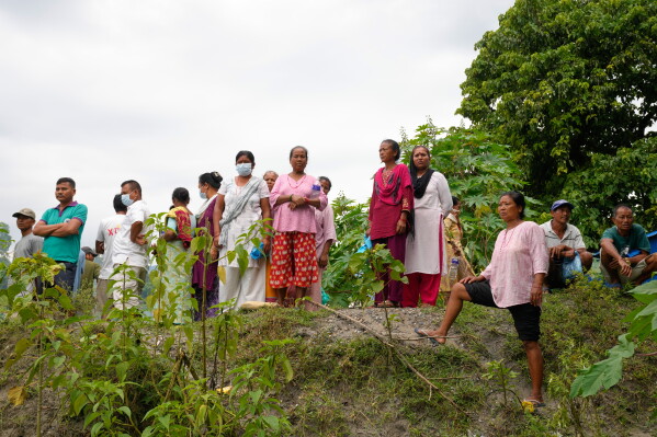 Onlookers watch as volunteers and rescuers carry the body of a flash flood victim for mass burial in Chitwan, Nepal, Monday, Aug. 31, 2026. (AP Photo/Dar Yasin)