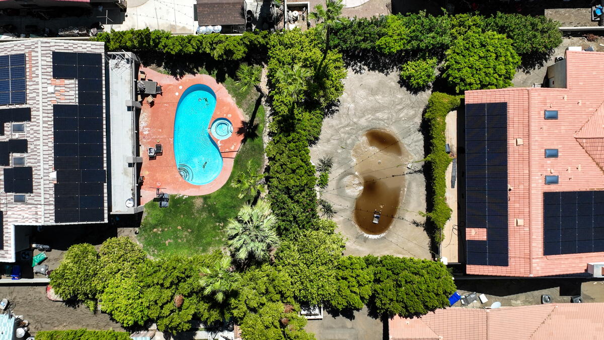 Aerial photo showing one backyard pool covered with mud from floodwaters.