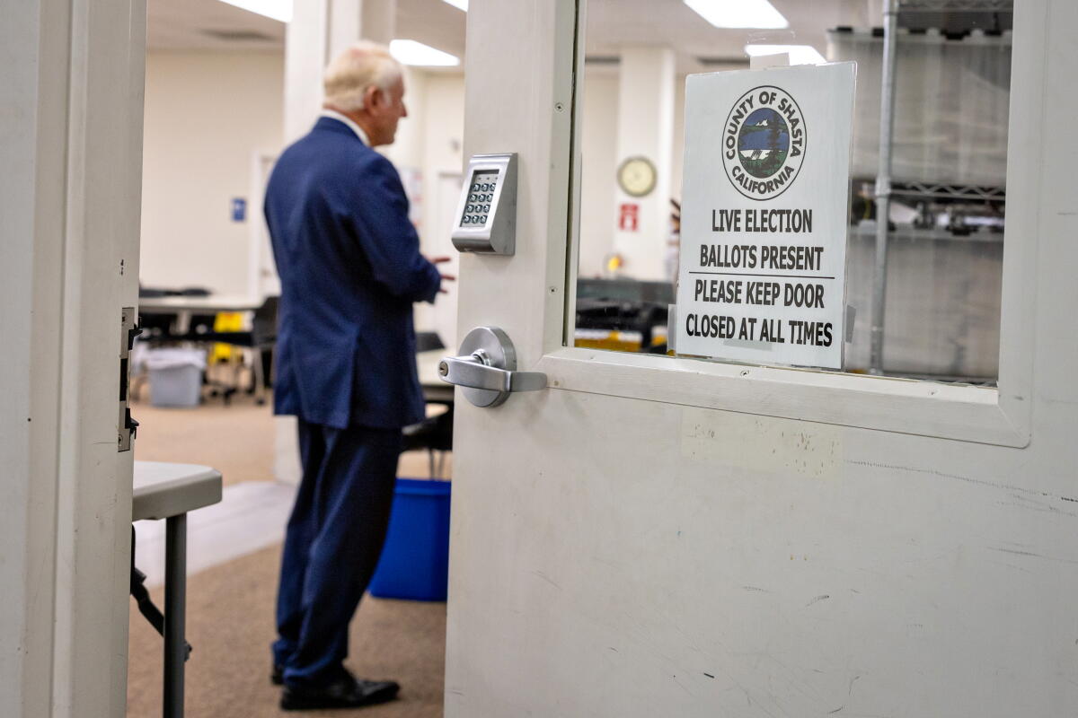A man stands in an doorway near a sign: "Live election ballots present - please keep this door closed at all times."