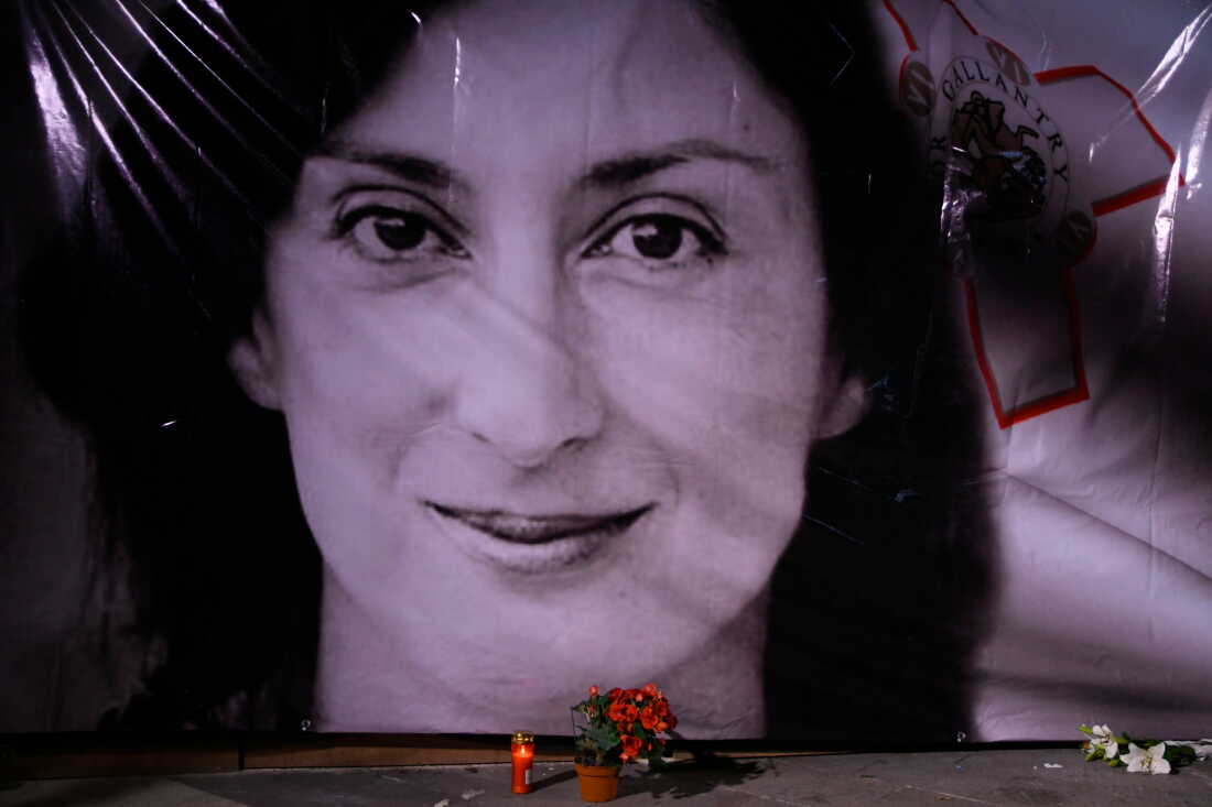Flowers and a candle lie in front of a portrait of slain investigative journalist Daphne Caruana Galizia during a vigil outside the law courts in Valletta, Malta, Oct. 16, 2018.