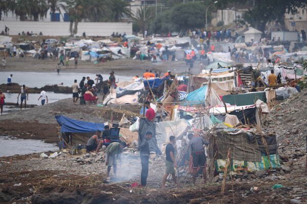 Migrants stand near their tents at El Trampolín beach in the Spanish exclave of Ceuta, Wednesday, Sept. 2, 2026. (AP Photo/Francis González)