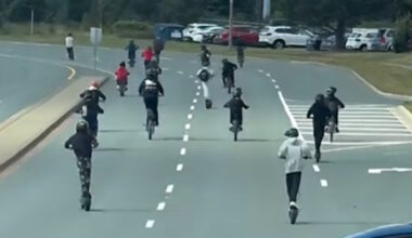Group of Young People Riding E-Scooters on Busy Roadway Making Rounds Online