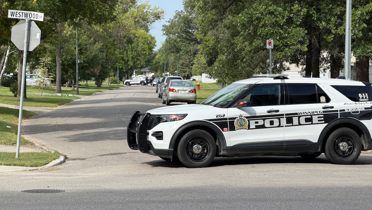 A police vehicle with black and white text on the side that reads "Winnipeg Police" is parked on a residential street