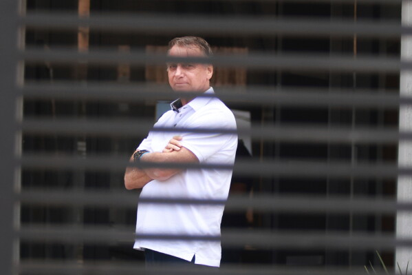 Brazil's former President Jair Bolsonaro stands at the entrance of his home while he is under house arrest in Brasilia, Brazil, Sept. 2, 2025. (AP Photo/Luis Nova, File)