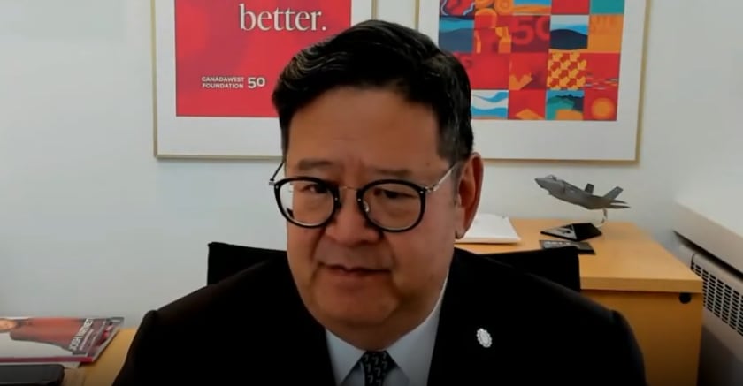 A man with glasses sits at a desk