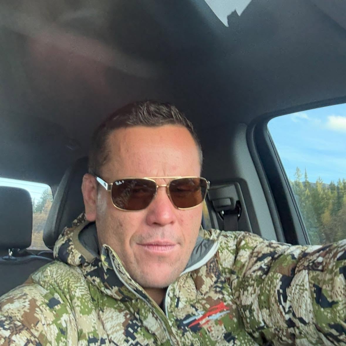 A man wearing sunglasses and driving.