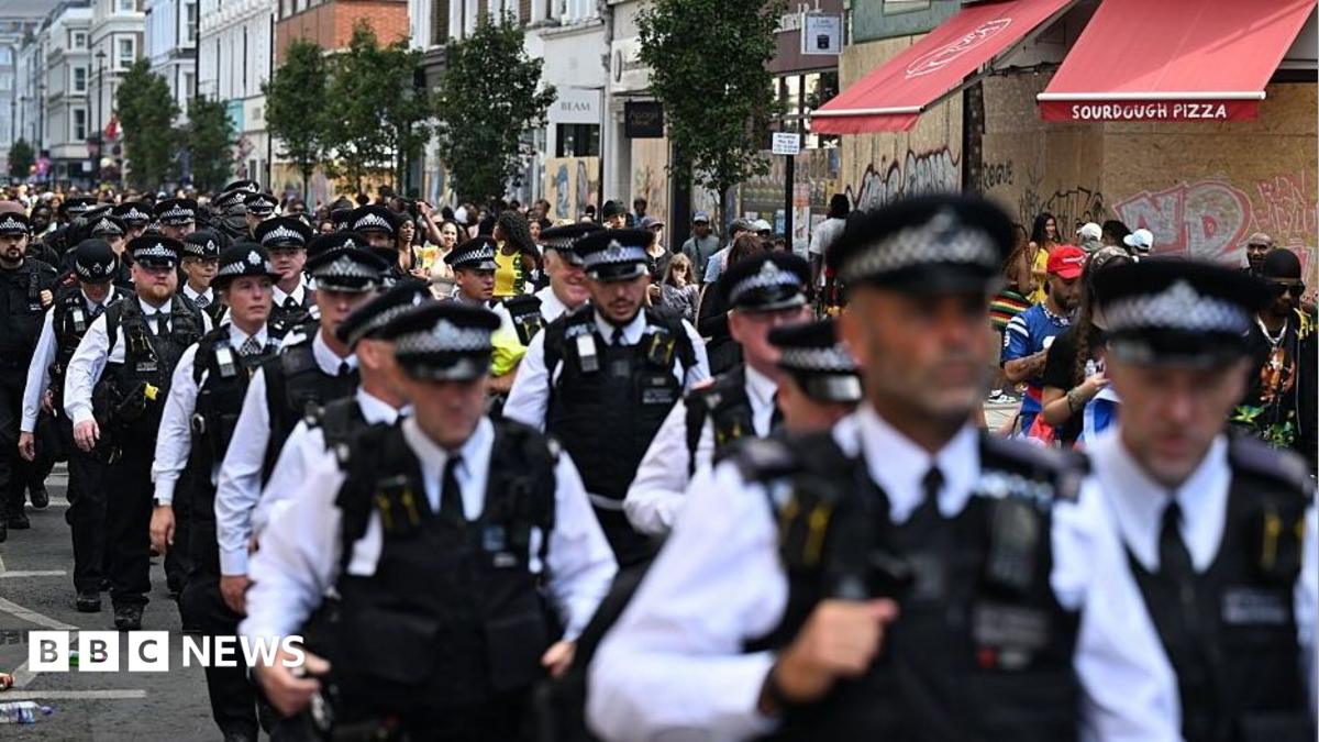 Dozens of members of the Metropolitan Police walk in uniform through the Notting Hill Carnival