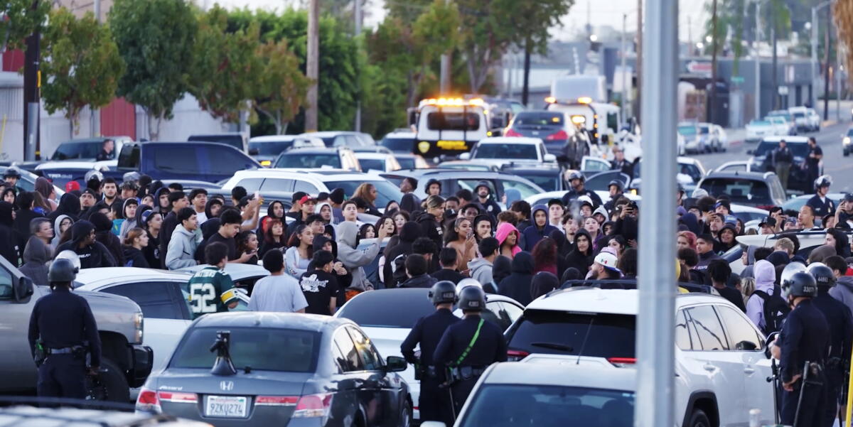 A crowd of people and police standing amid a crush of vehicles, including tow trucks