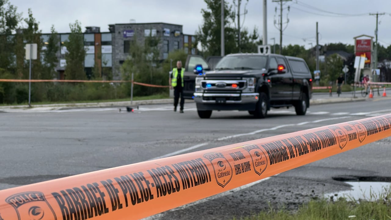 A police car and drone past police tape on a cloudy day.