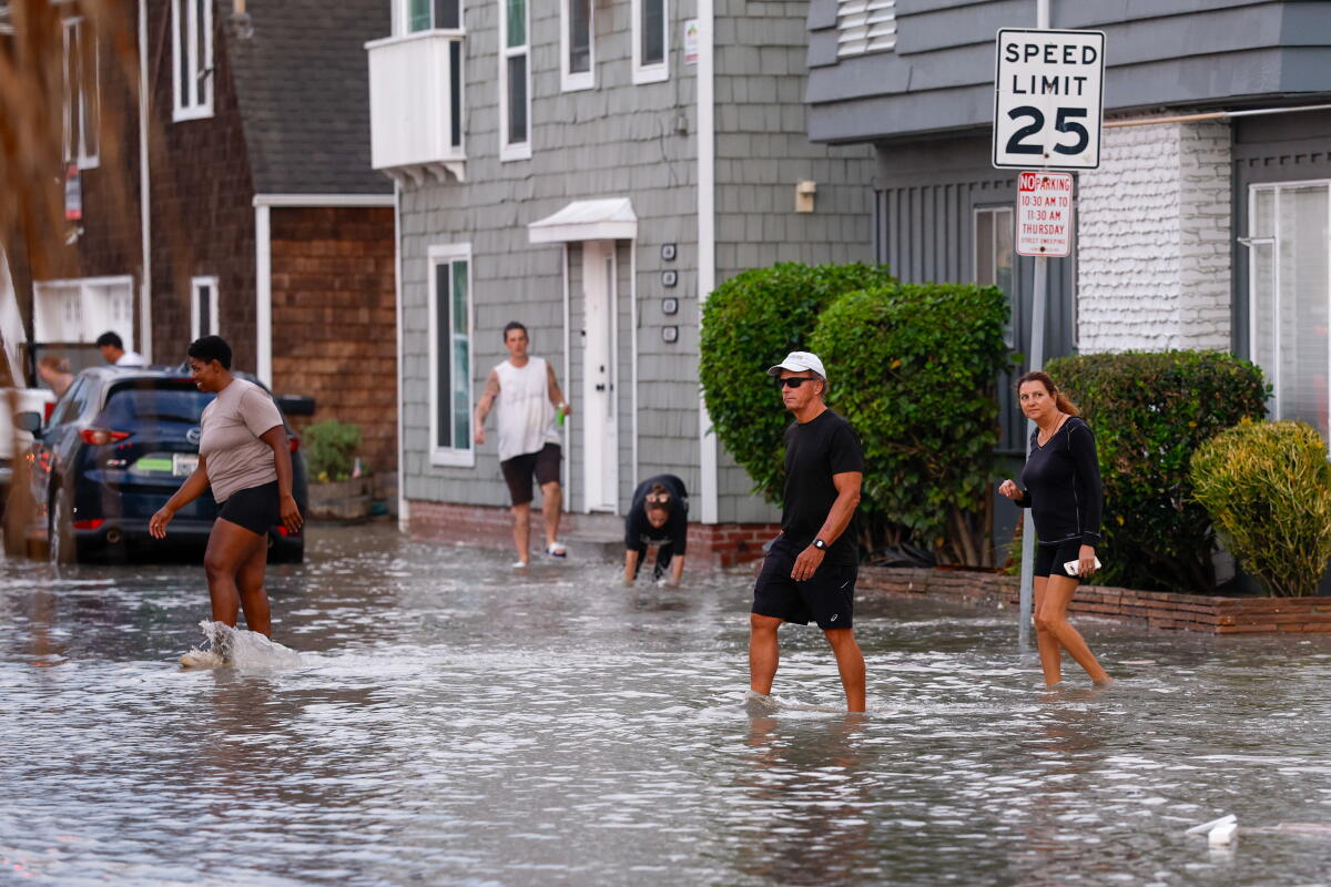 People walk through a flooded street.  