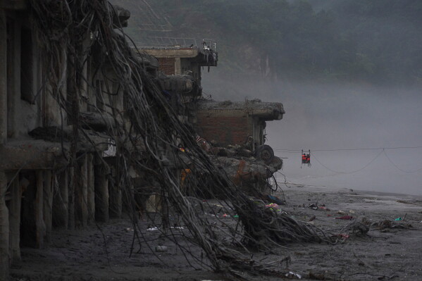 Residents commute across the Trishuli river on a newly installed zipline in the aftermath of flash floods in Devighat, Nuwakot district, Nepal, Monday, Sept. 7, 2026. (AP Photo/Niranjan Shrestha)