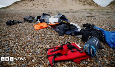 A red life jacket, bags, and other belongings left abandoned on a stony beach, following the death of at least 30 migrants on the English channel in November 2021