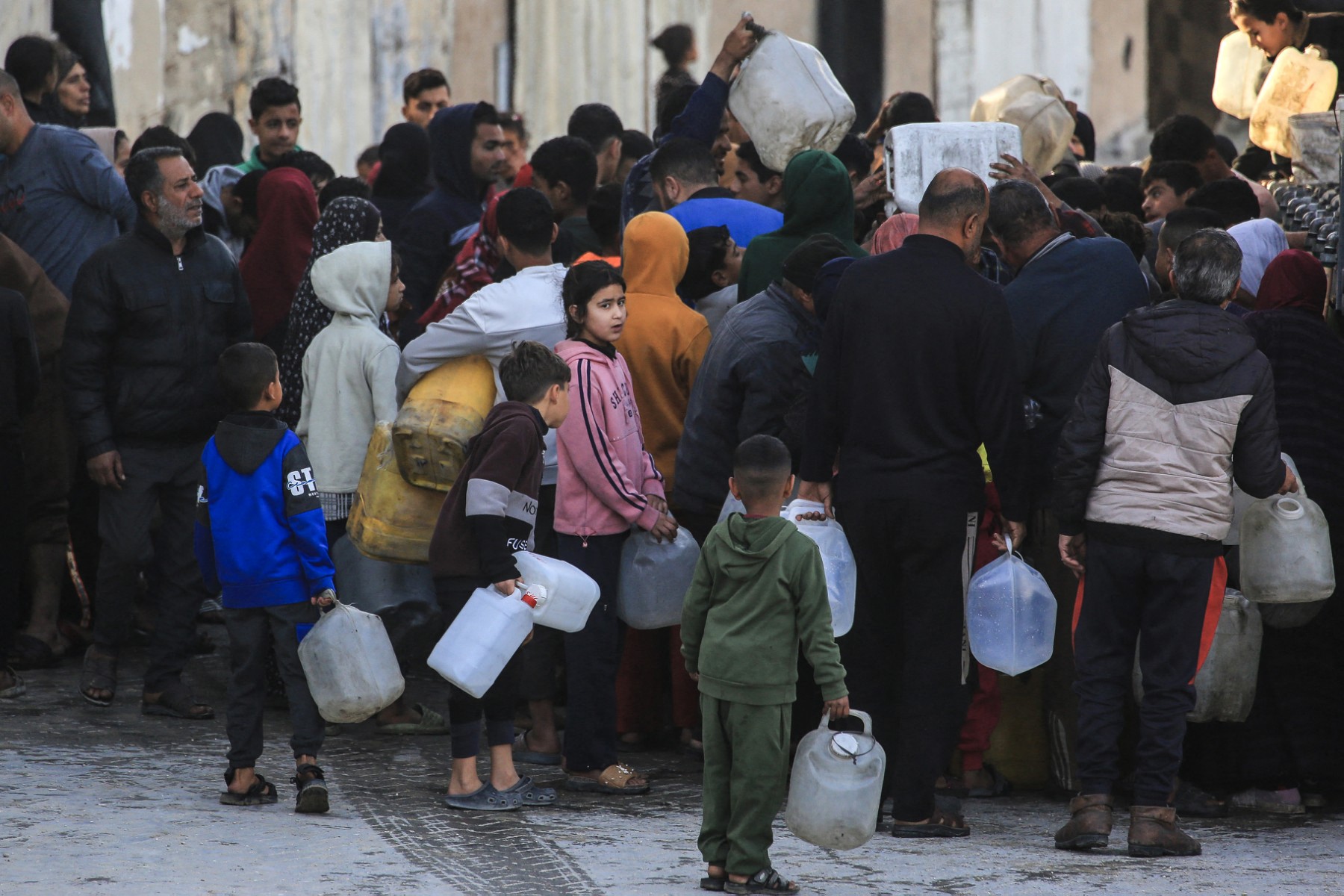 Displaced Palestinians wait to fill jerrycans with water collected from a desalination plant in Khan Yunis, southern Gaza Strip, on February 7, 2026. (AFP)