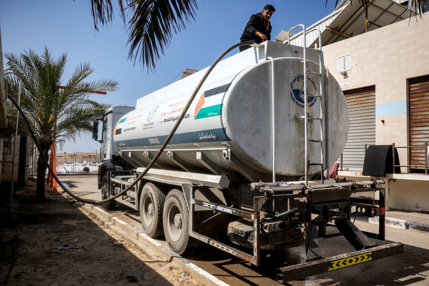 A man fills up a water tanker parked at the Southern Gaza Desalination plant, which stopped working earlier after Israel cut off electricity supply to the Gaza Strip, in Deir El-Balah on March 10, 2025.