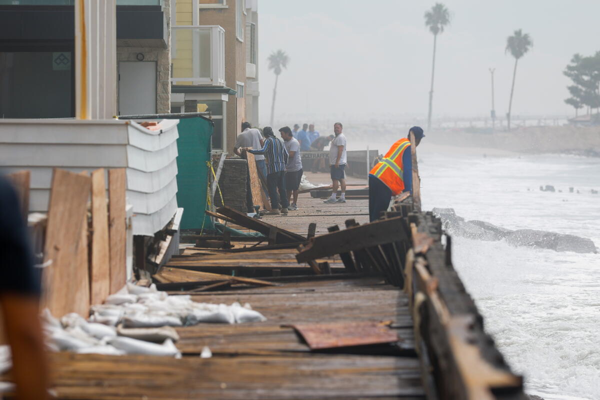 Officials and residents assess the damage Tuesday to homes and the boardwalk on the Alamitos Peninsula in Long Beach.