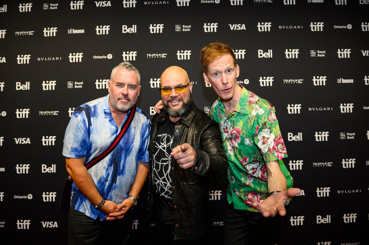Three men in front of a sign