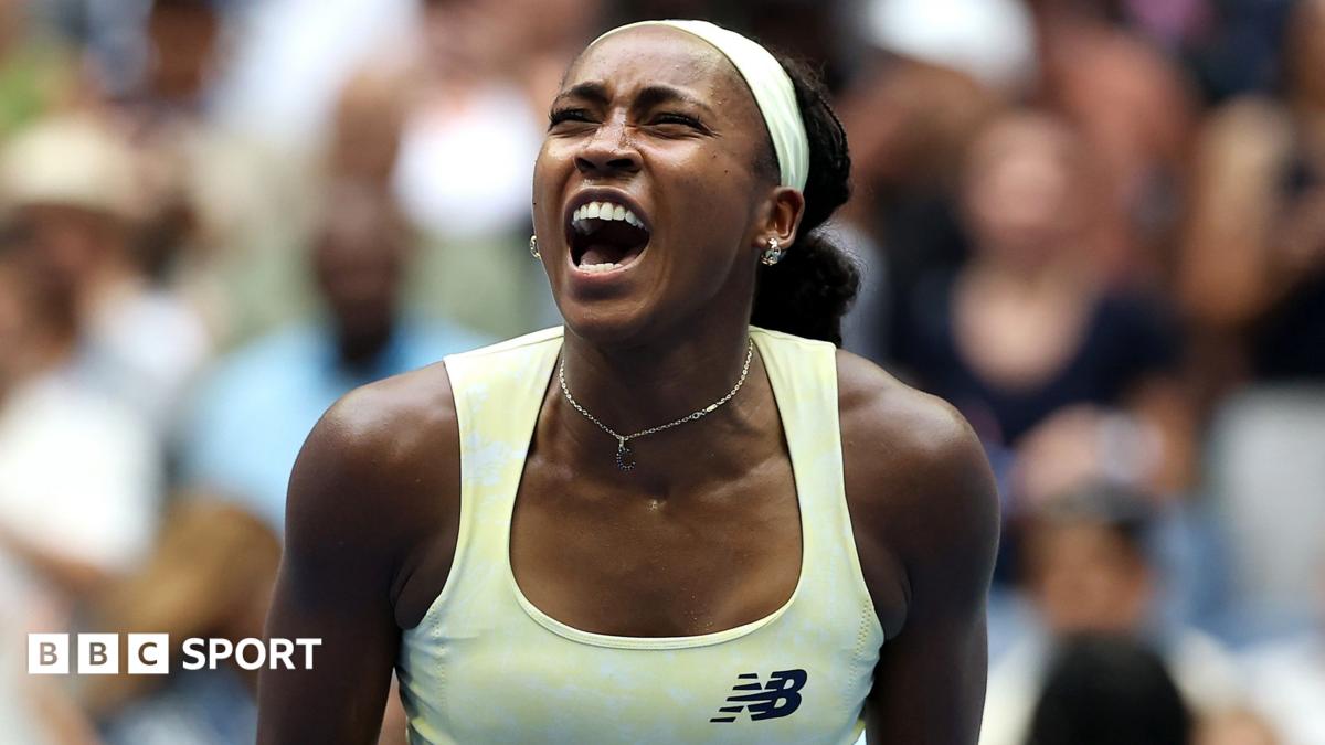 Coco Gauff, wearing a pale yellow vest, puts her left index finger behind her ear
