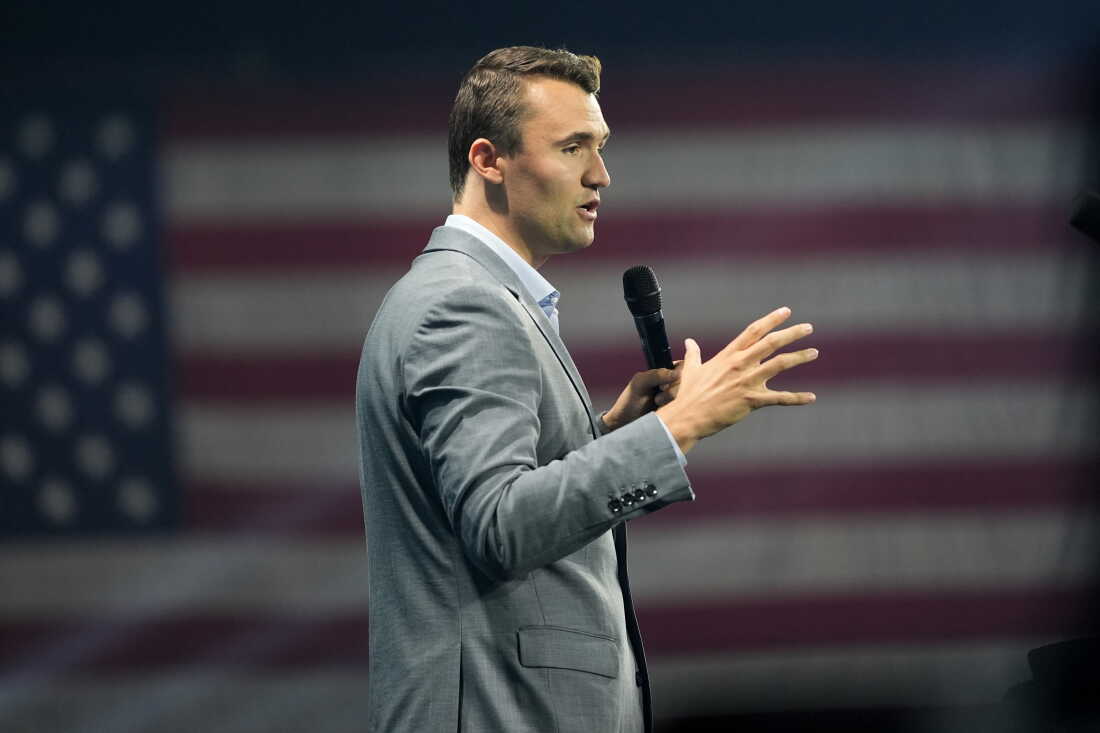 Holding a microphone and wearing a gray suit, Charlie Kirk speaks at Turning Point's Believers' Summit on July 26, 2024, in West Palm Beach, Florida.