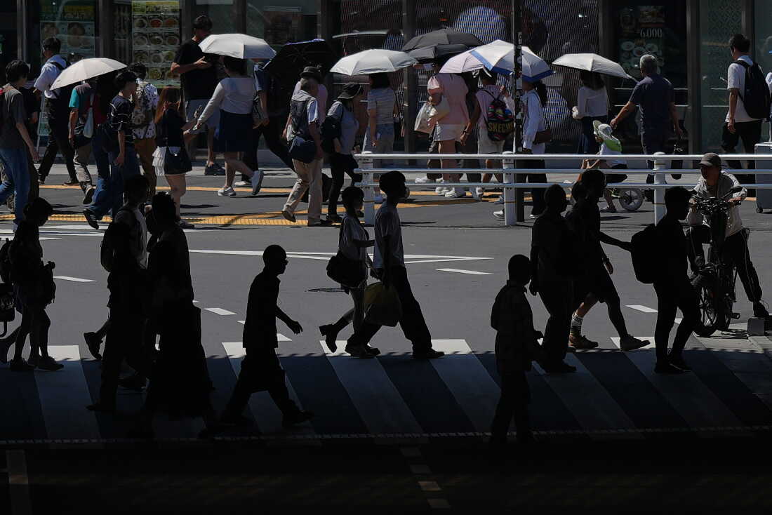 People walk a pedestrian crossing under the scorching sun Tuesday, Aug. 25, 2026, in Tokyo.