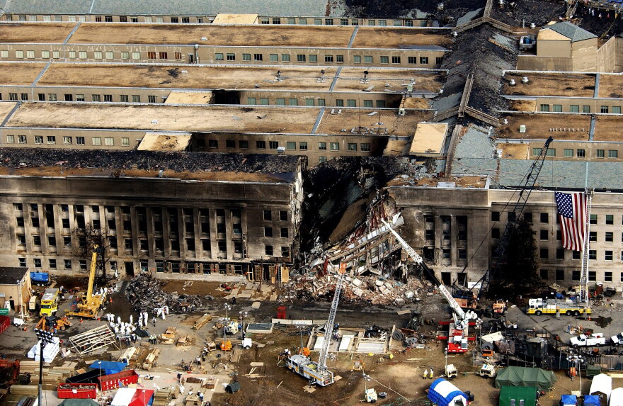 Photo of a building that is partially destroyed. There is emergency equipment around it.
