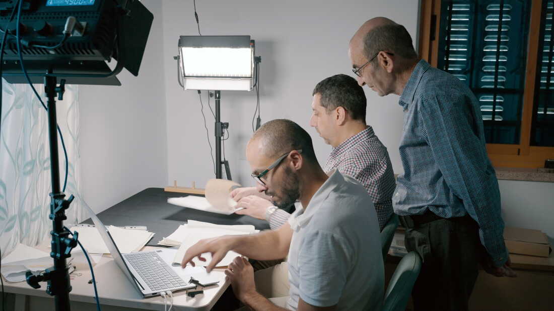 Yazeed Abu Khdeir (left) and Mahmoud Muna work to digitize papers, as Raja Shehadeh (standing) looks on August 2025.