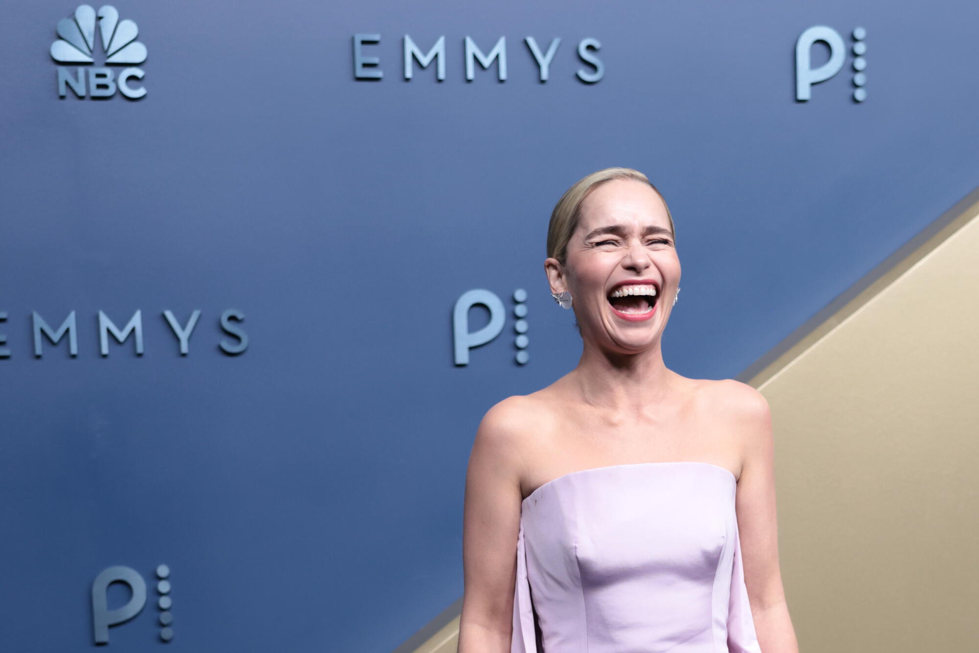 Emilia Clarke laughs on the Emmys blue carpet. 