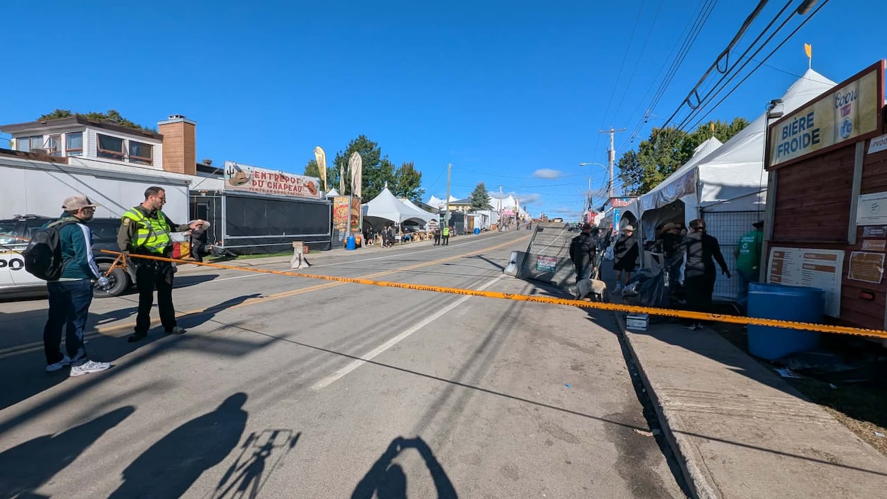 police tape across a road with festival tent vendors on either side.