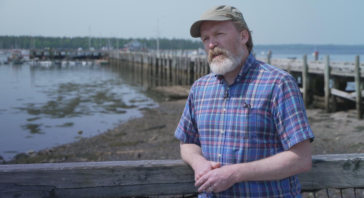 A man stands in front of a wharf.
