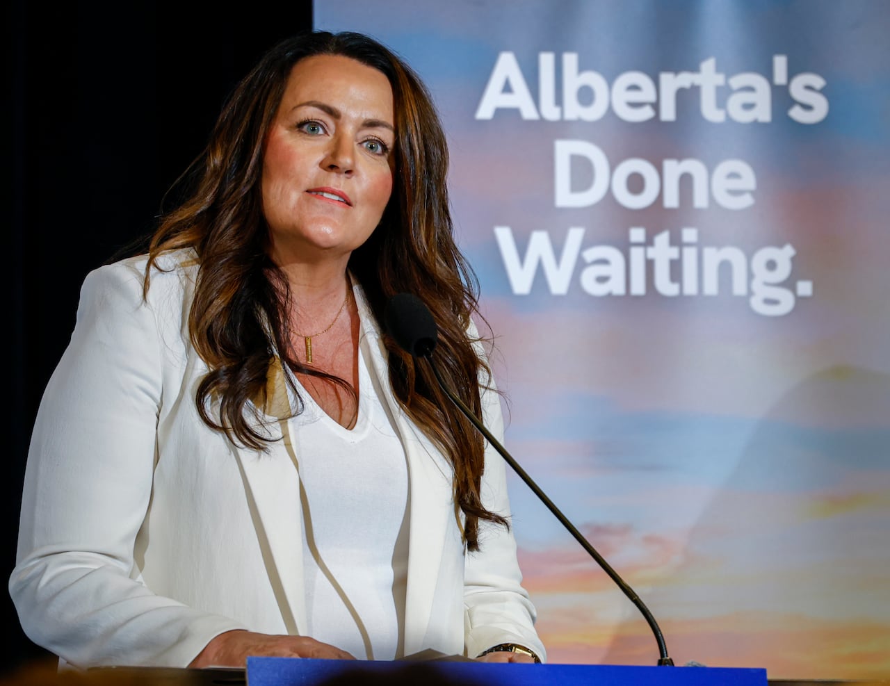 Person speaks in front of a sign saying "Alberta's done waiting."