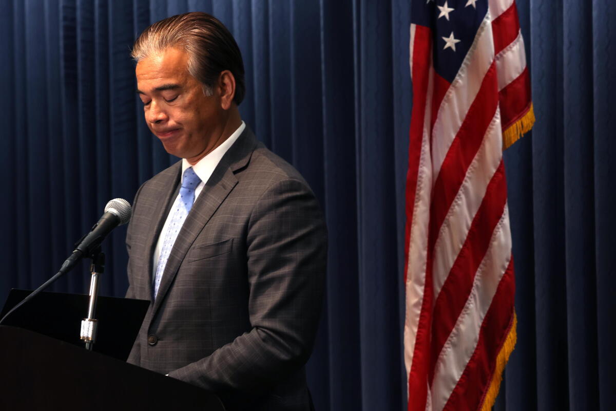 Rob Bonta looks down while standing next to a U.S. flag