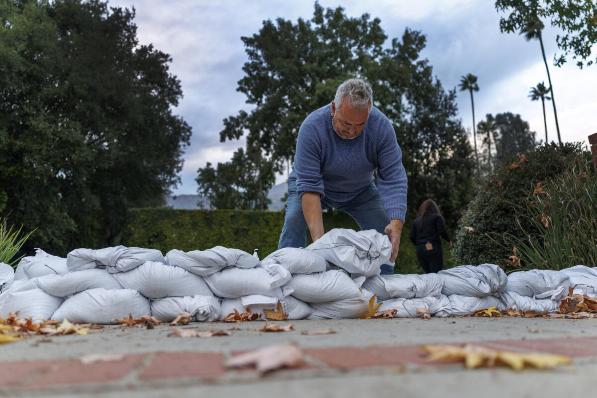 Bob Ganguin of Altadena places sandbags at the end of his driveway.