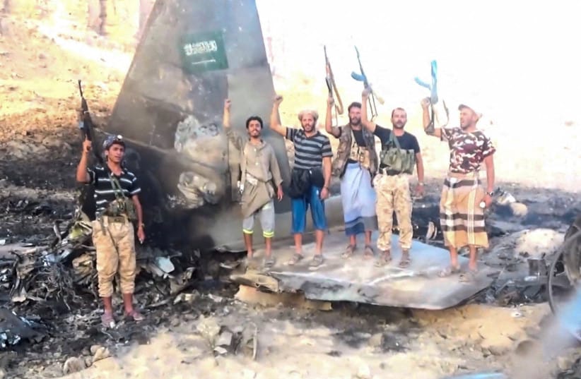 Houthi fighters stand in front of what they say is a downed Saudi jet, at a location given as Yemen, in this still image from a handout video released on September 16, 2026.