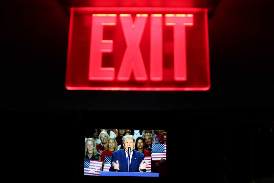 Seen on a screen below an exit sign, President Trump speaks on the first day of the 2026 Republican convention on Sept. 9 in Dallas.