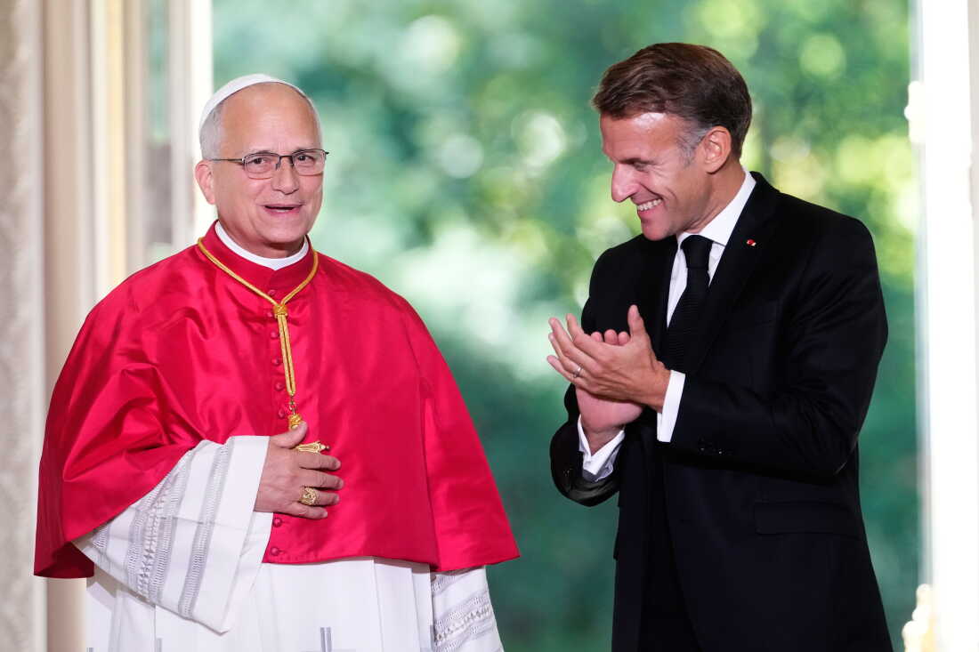 Pope Leo XIV stands with an applauding French President Emmanuel Macron at the Élysée Palace in Paris, Friday.