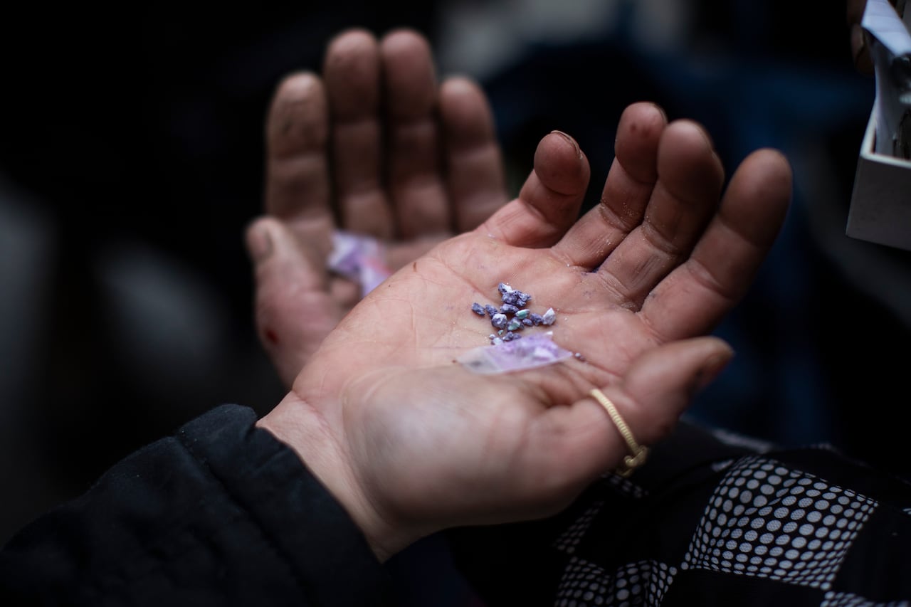 Purple crystals are held in a person's hand.