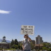A man holds a sign that says "not here not anywhere end AI."