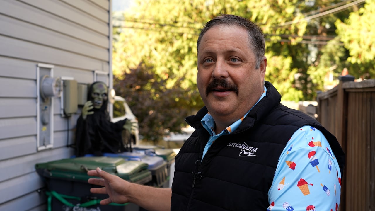 A man standing beside his garbage bins