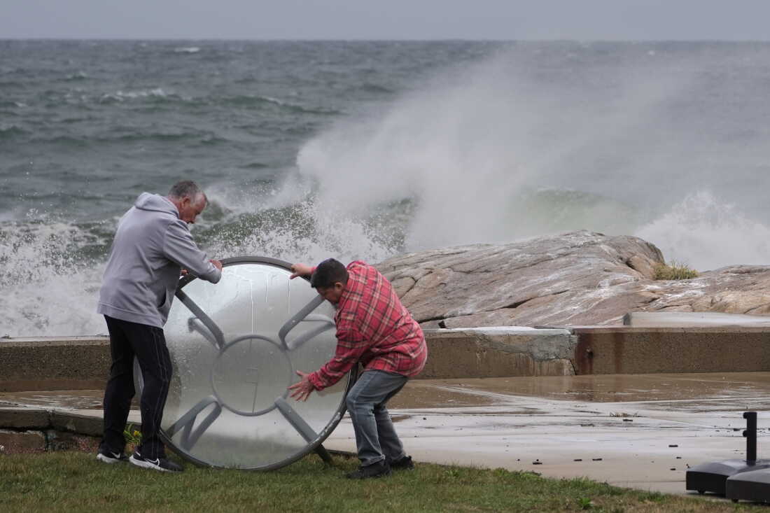 John Garrisi, left, and Gaige Graf move an outdoor table away from the shorefront during the early stages of a nor'easter storm on Friday.