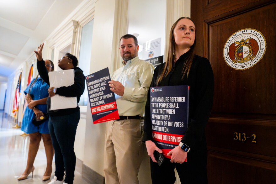 People Not Politicians Deputy Director Emily Gerber, right, and executive director Richard von Glahn, second from left, hold signs decrying the state’s attempt to gerrymander its congressional map to favor Republicans on Tuesday, Jan. 13, 2026, at the Capitol in Jefferson City.