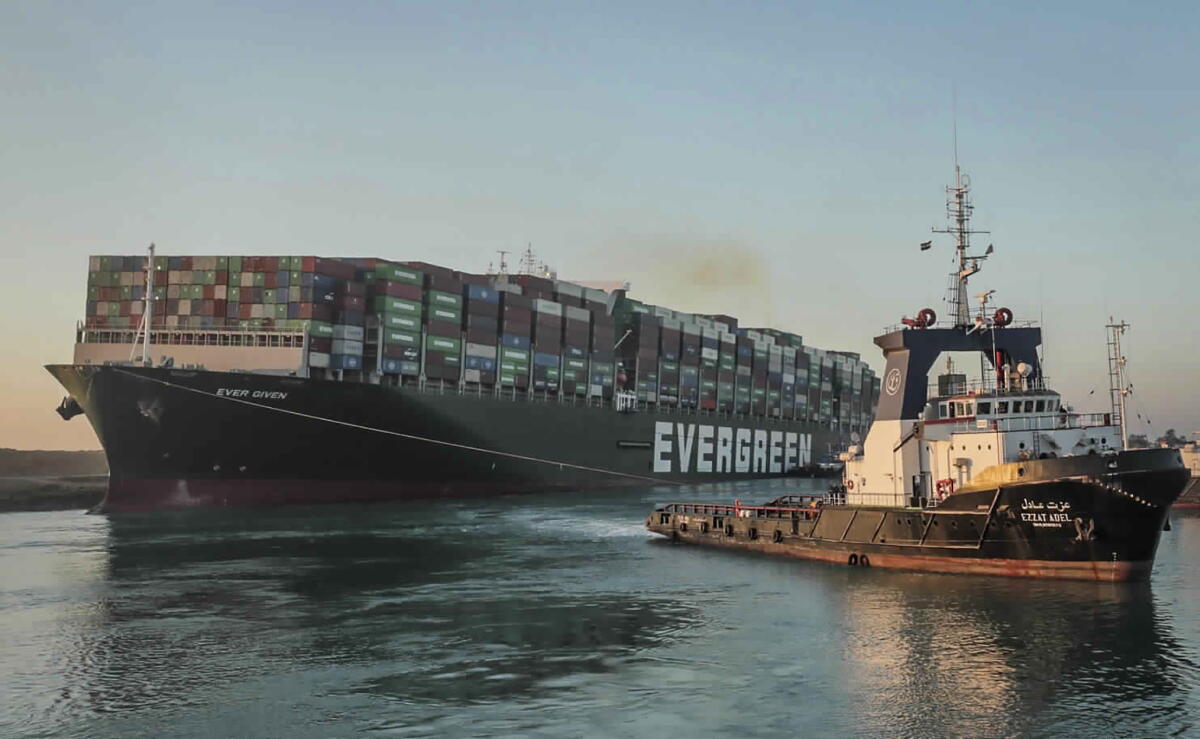 the Ever Given, a Panama-flagged cargo ship, is pulled by one of the Suez Canal tugboats