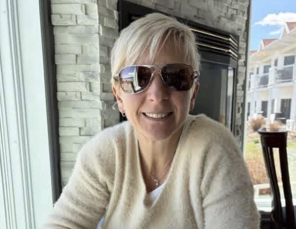 A women wearing sunglasses smiles.