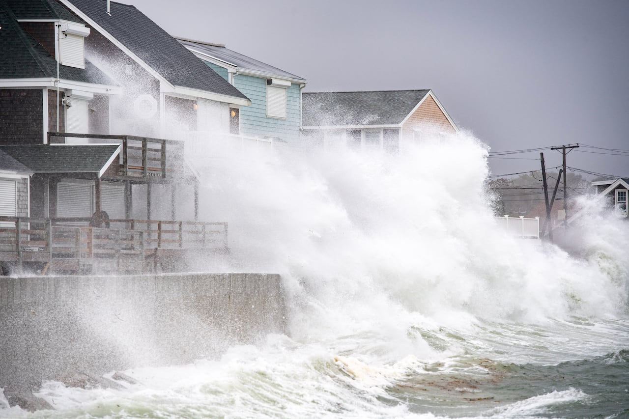 Powerful waves crash against houses.
