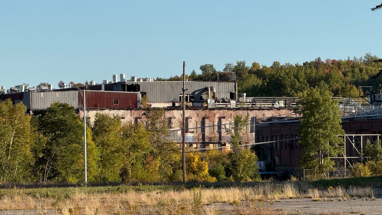 An abandoned paper mill building viewed from a distance.