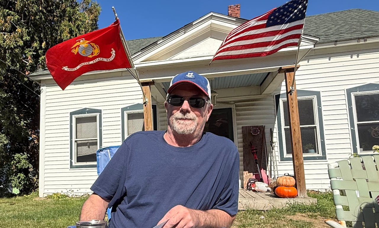 Chris Morang sits on a chair in front of a house.