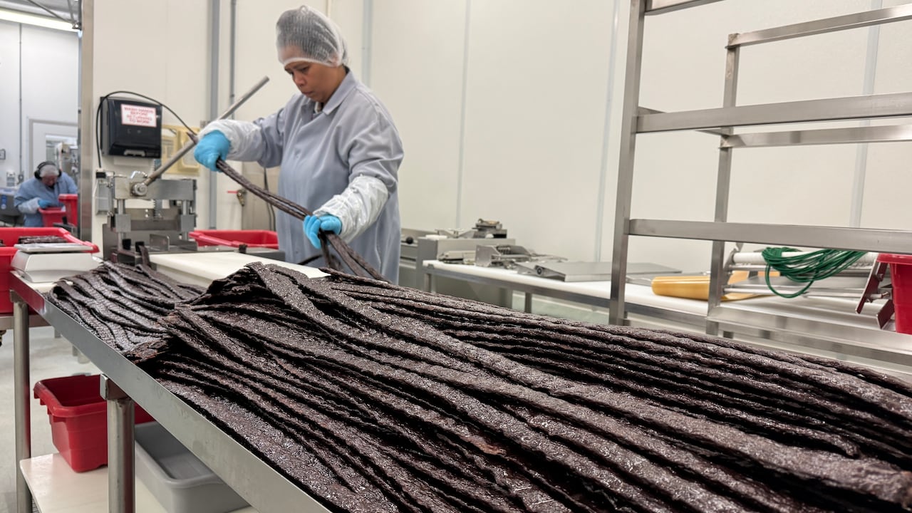 A woman in protective wear hold long strands of brown material.