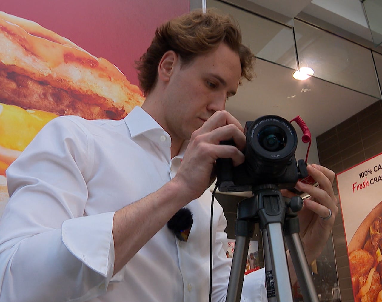 A man in a white shirt toys with a camera.